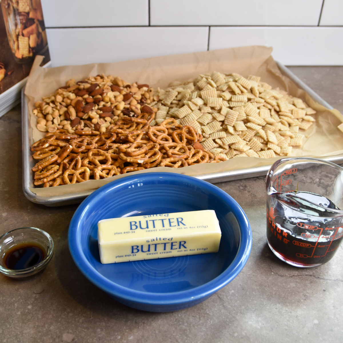 Ingredients for sorghum snack mix: Rice Chex, mini pretzels, mixed nuts, butter, sorghum syrup, vanilla, and M&Ms