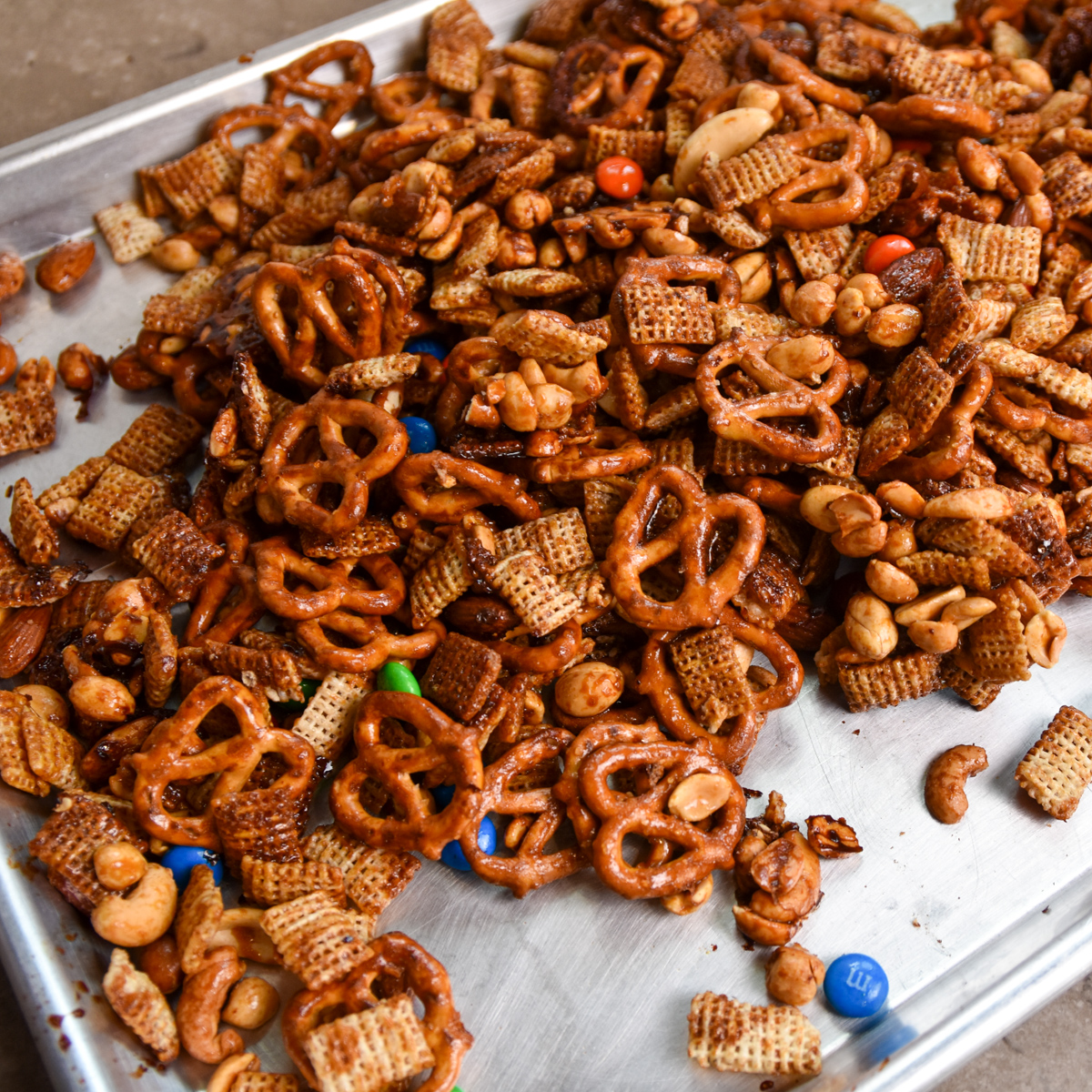 Sorghum cereal snack mix with Rice Chex, pretzels, nuts, and M&Ms in a sheet pan