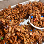 Sorghum cereal snack mix with Rice Chex, pretzels, nuts, and M&Ms in a serving bowl