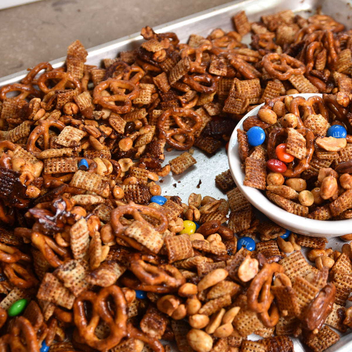 Sorghum cereal snack mix with Rice Chex, pretzels, nuts, and M&Ms in a serving bowl