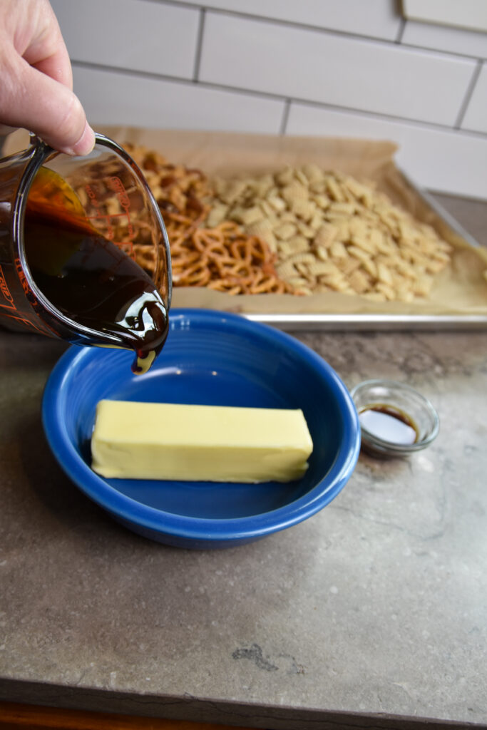 Adding sorghum syrup to stick of butter in blue bowl