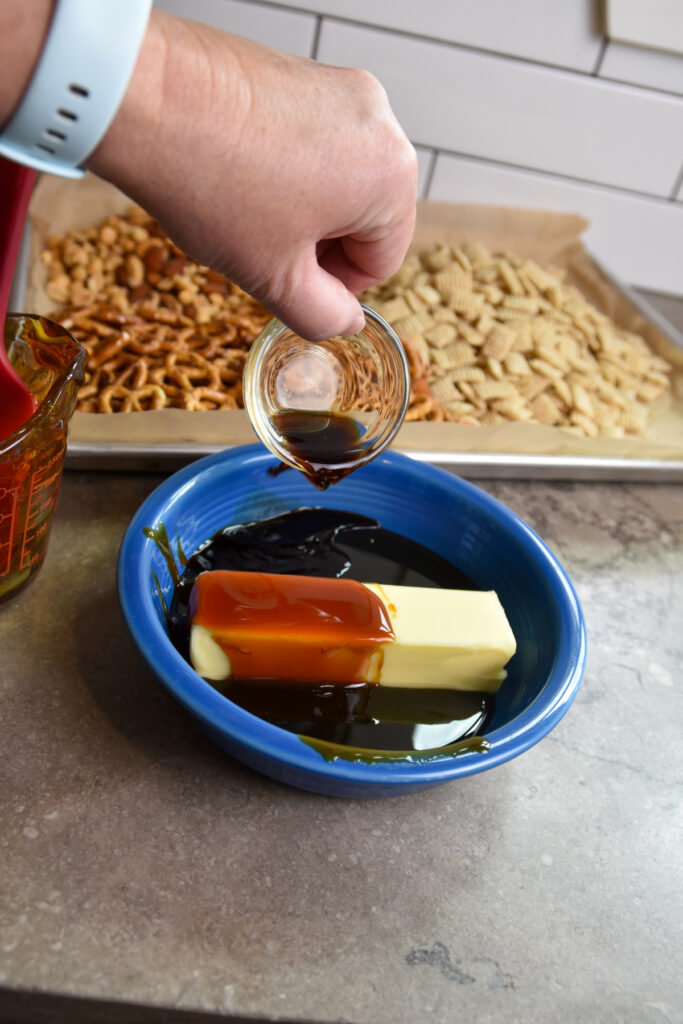 Butter, sorghum syrup, and vanilla in a glass bowl ready to be melted for snack mix coating