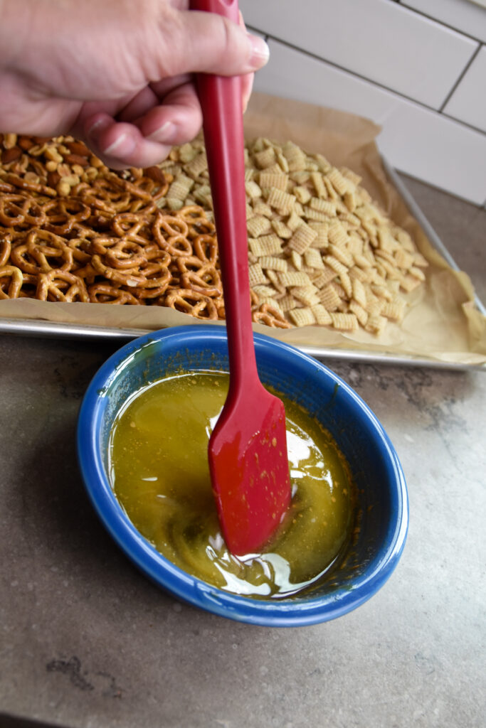Melted butter, sorghum syrup, and vanilla in a glass bowl for snack mix coating