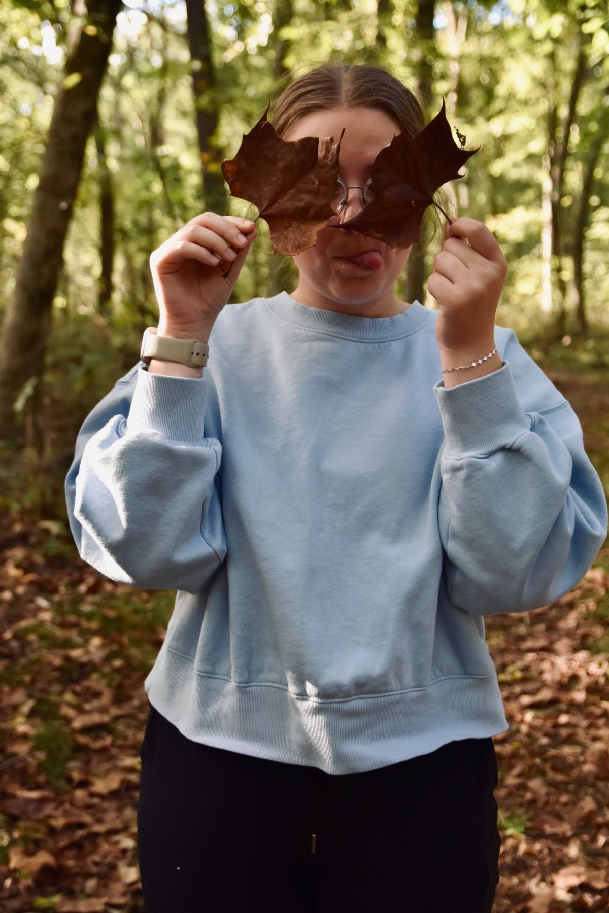 Holding up leaves over her eyes.