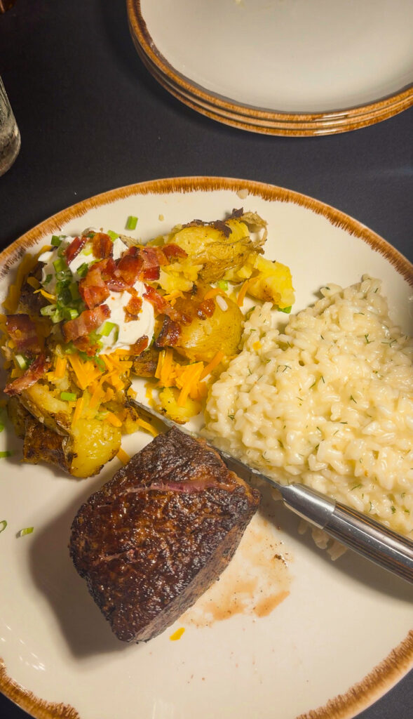 Plate with steak, baked potato, and risotto.